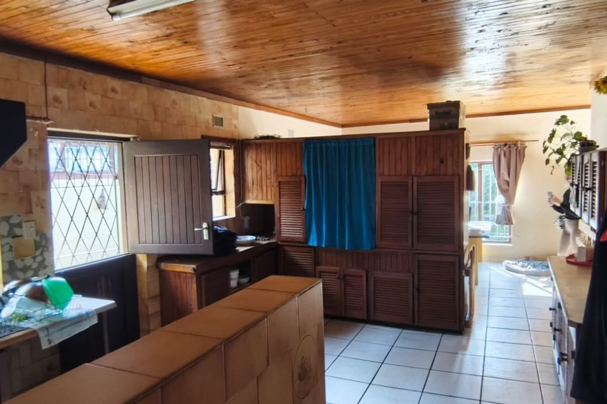 A dated kitchen featuring extensive wooden cabinetry, tiled wall finishes, and a wooden ceiling, offering significant potential for a modern renovation.