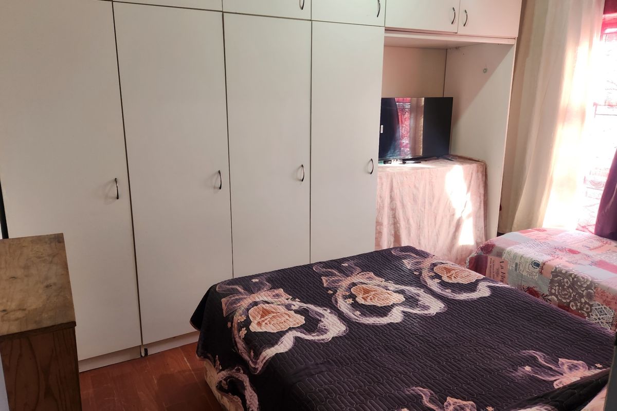 A bedroom featuring extensive floor-to-ceiling built-in wardrobes and laminate flooring, offering ample storage space.