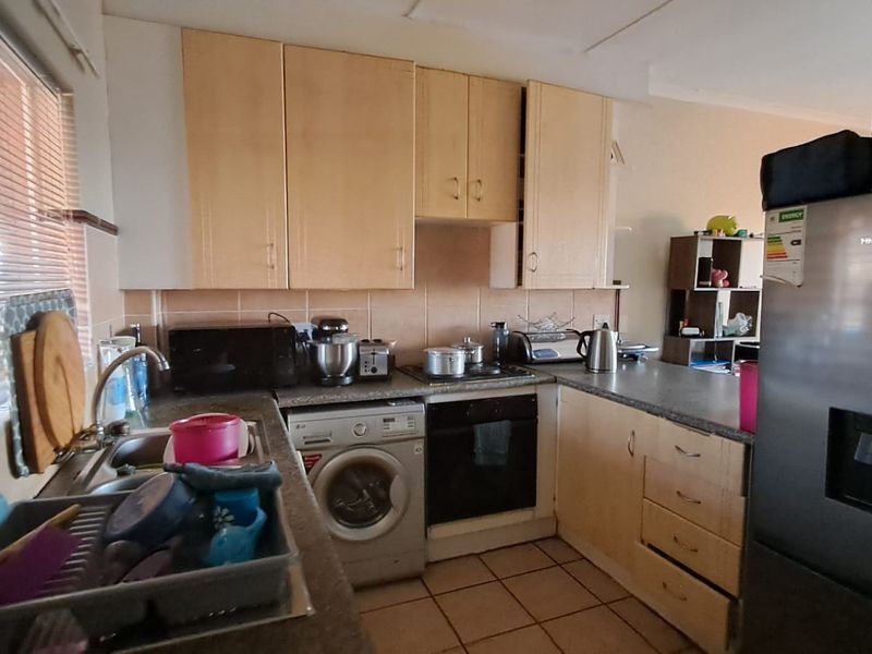 Functional kitchen featuring laminate cabinetry, tiled backsplash, built-in oven, hob, and tiled flooring, providing a practical workspace for daily cooking needs.