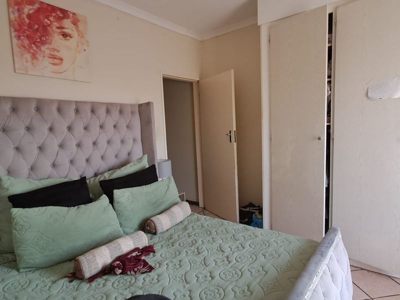 A bedroom featuring built-in cupboards, tiled flooring, and neutral wall finishes, providing a functional space with storage.