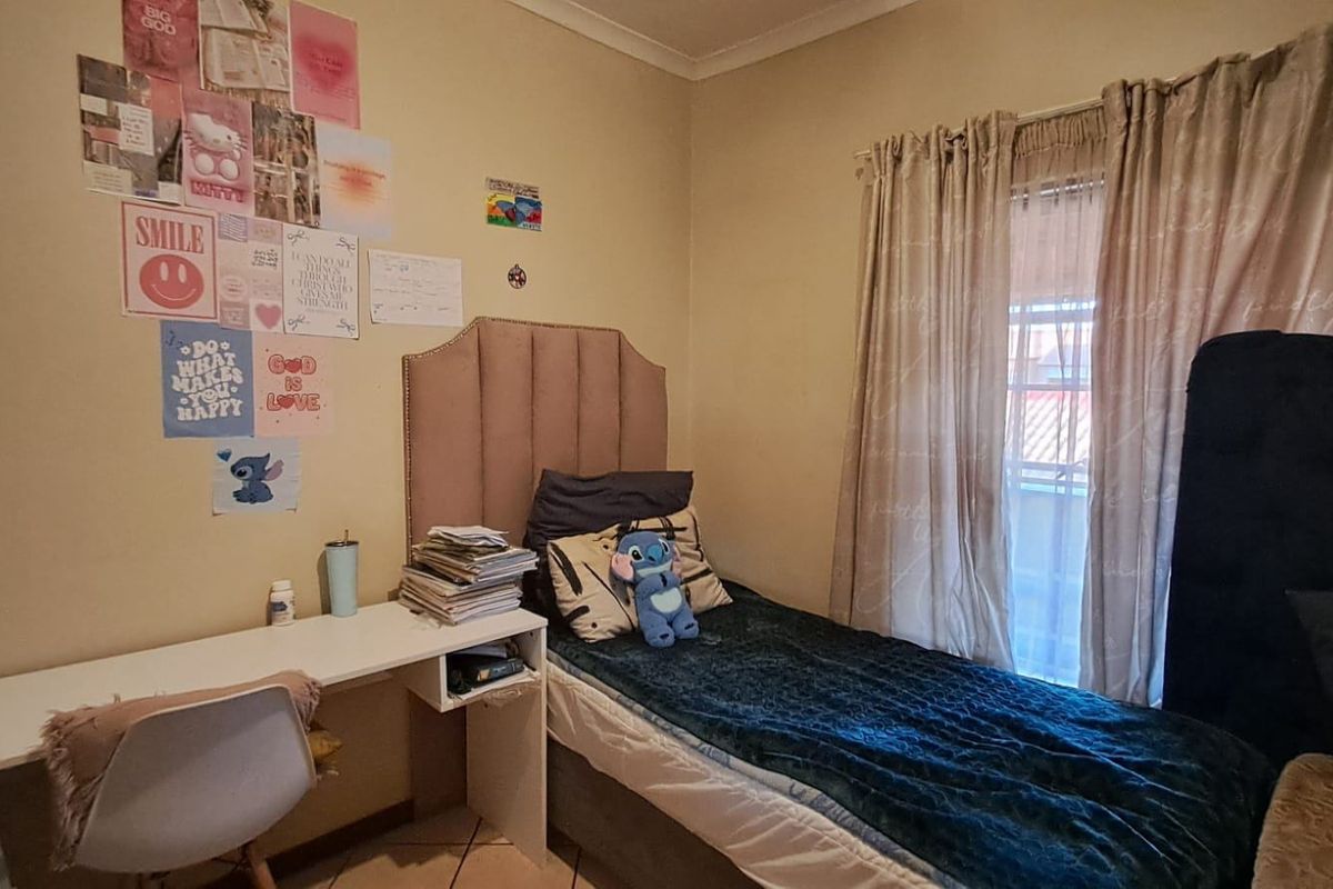 A functional bedroom featuring tiled flooring and access to a balcony through a window with curtain tracks.