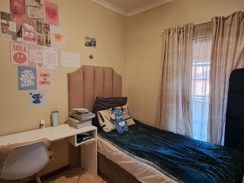 A functional bedroom featuring tiled flooring and access to a balcony through a window with curtain tracks.