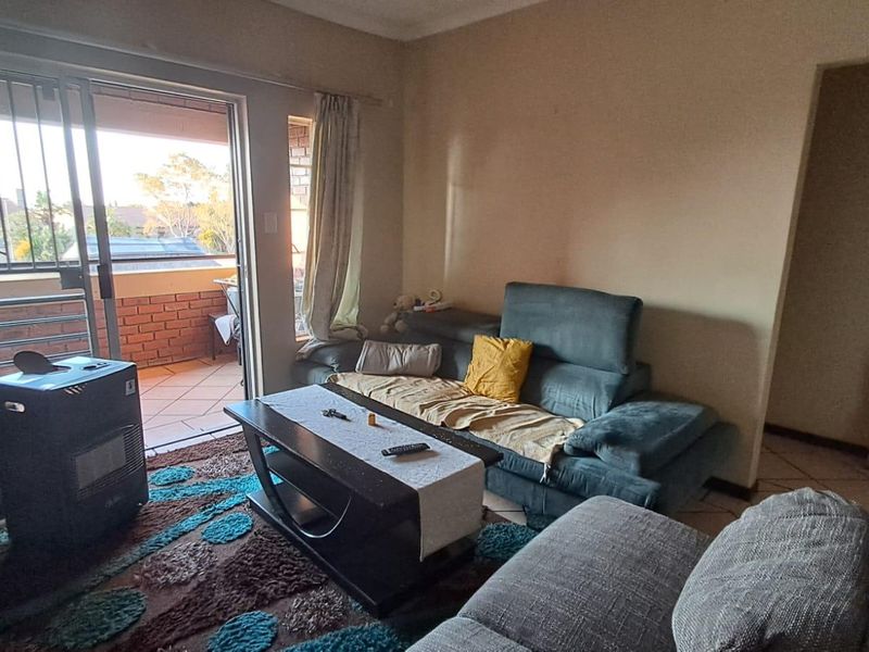 A living room featuring tiled flooring and a sliding glass door providing direct access to an outdoor balcony area.