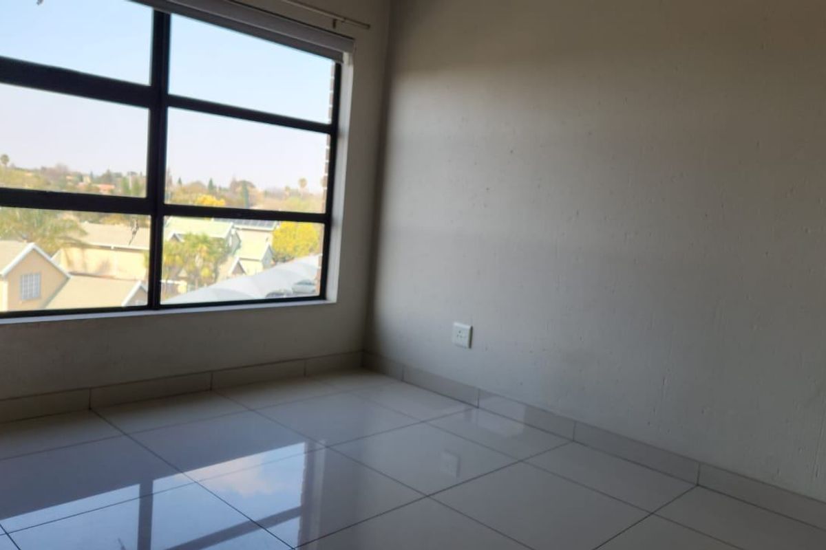 A bright, empty bedroom featuring large windows with natural light and clean tiled flooring, offering a blank canvas for personalization.