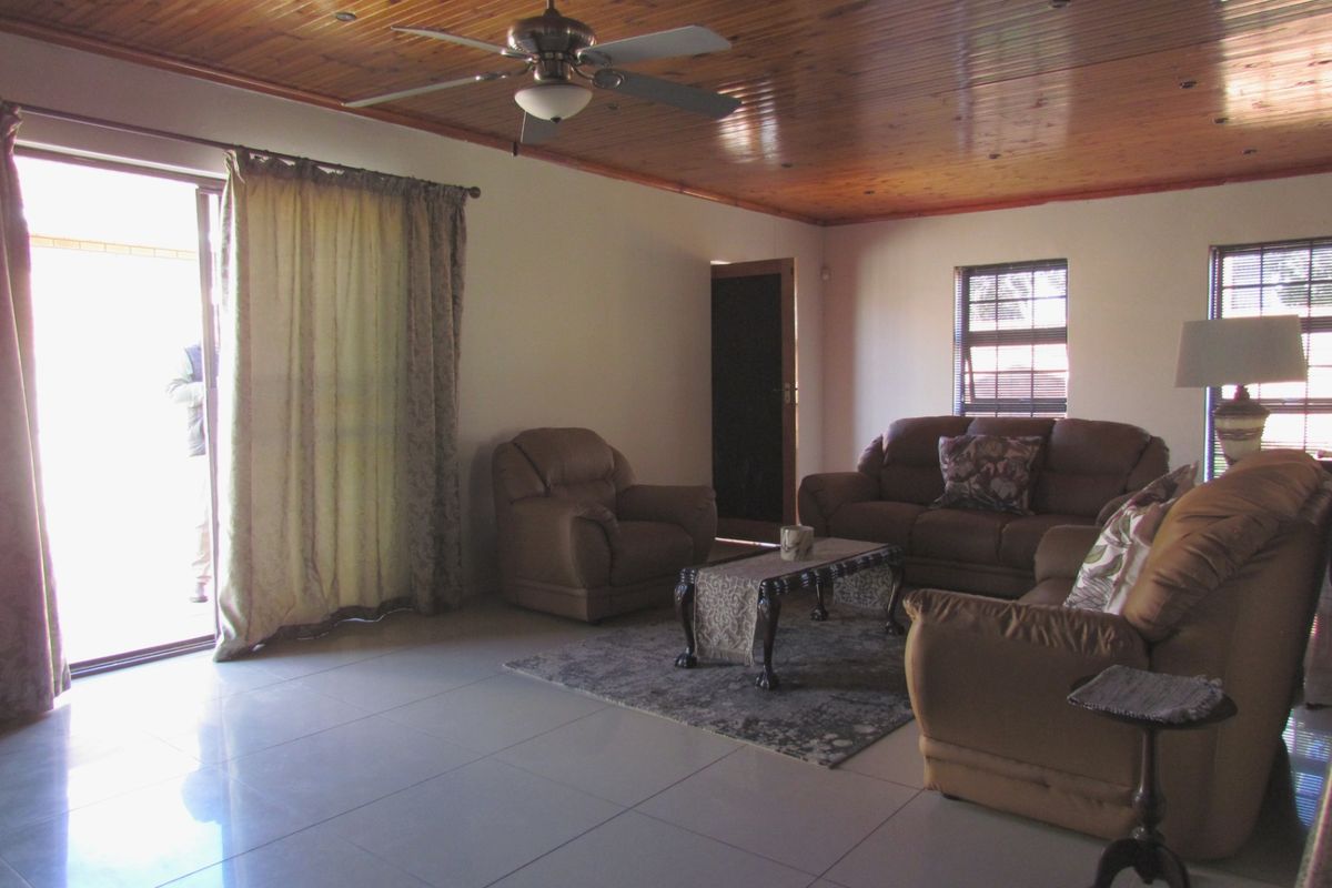 Spacious living room featuring a warm timber tongue and groove ceiling, tiled flooring, and direct access to the outdoors via a sliding glass door.