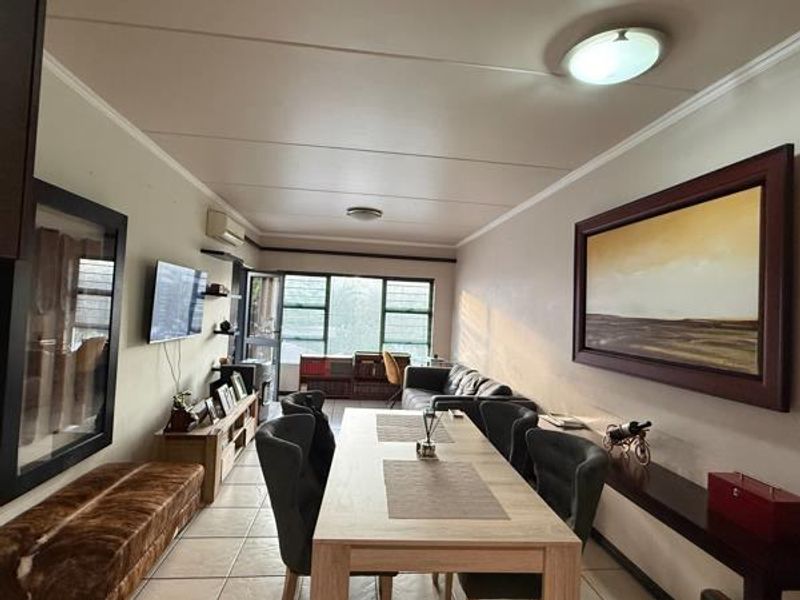 Open-plan living and dining area featuring tiled flooring, split-system air conditioning, and large windows providing natural light.