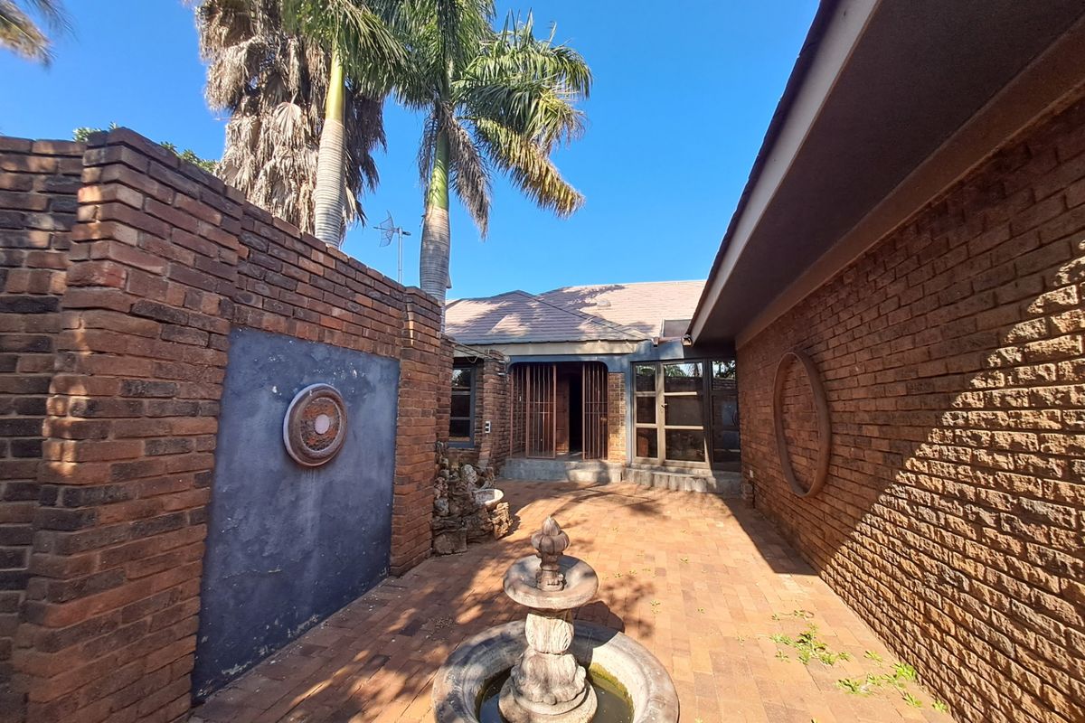 A private rear courtyard featuring face brick walls, paved flooring, and a central stone water fountain, providing a secluded outdoor space.