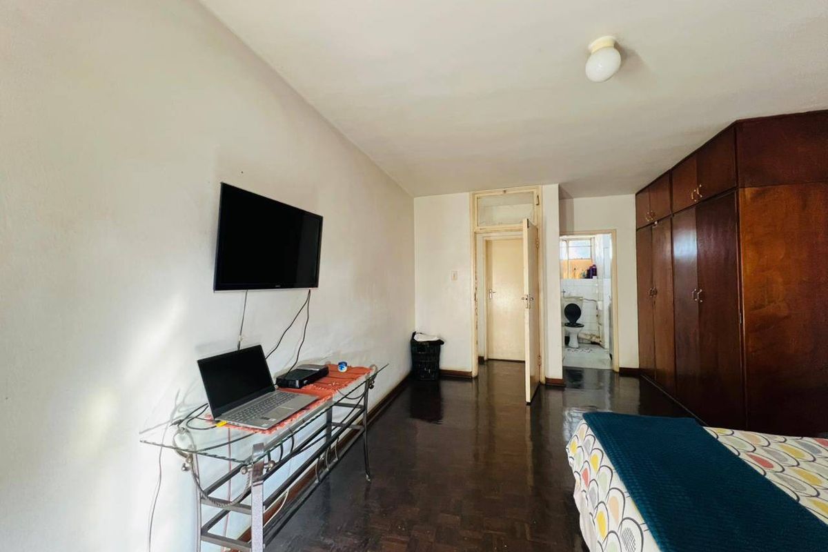 Bedroom featuring dark parquet flooring, extensive built-in wooden cabinetry, and direct access to an en-suite bathroom.