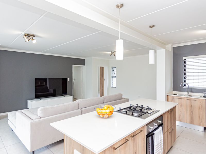 Modern open-plan living area featuring a contemporary kitchen with a central island, gas hob, and sleek cabinetry, seamlessly flowing into the lounge space.