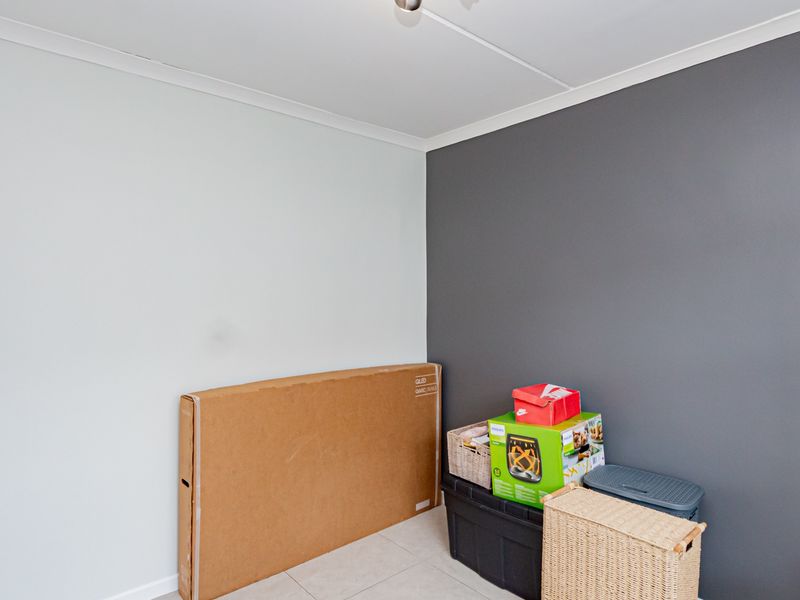 A simple bedroom space featuring neutral and dark grey painted walls with tiled flooring and ceiling coving.