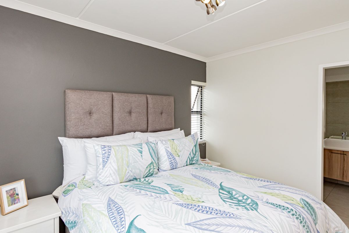 A well-maintained bedroom featuring a neutral color palette, modern ceiling lighting, and direct access to an adjoining en-suite bathroom.