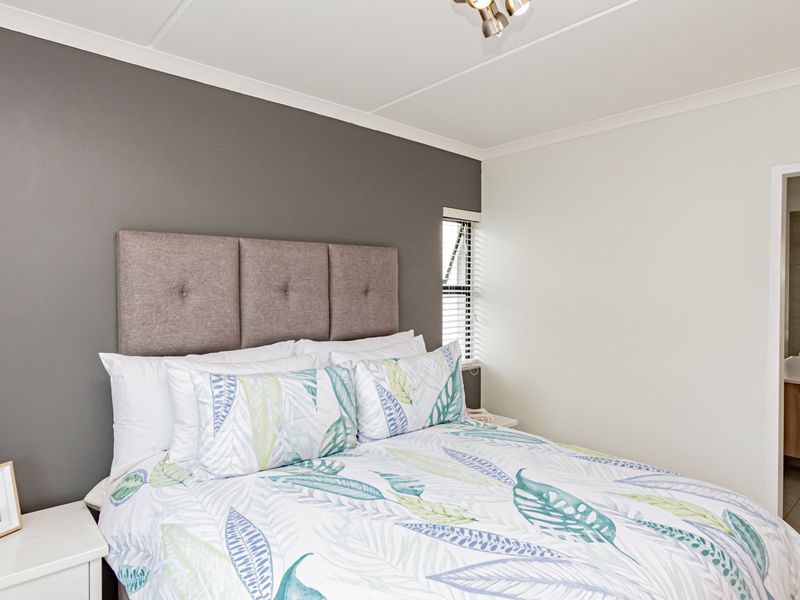 A well-maintained bedroom featuring a neutral color palette, modern ceiling lighting, and direct access to an adjoining en-suite bathroom.