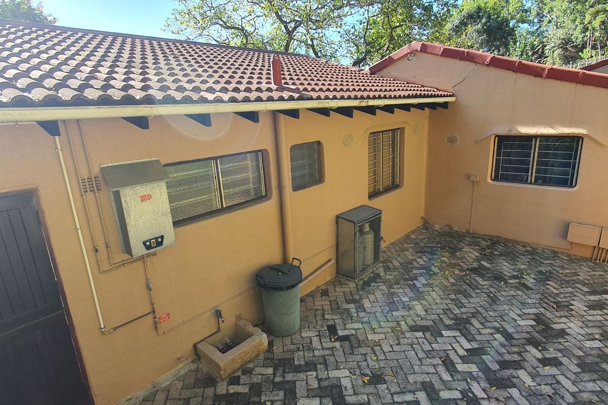 Rear exterior view of the townhouse featuring a paved courtyard, gas geyser installation, and secure window bars.