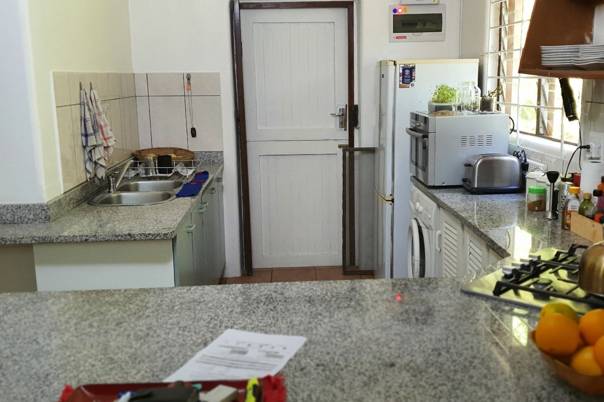 Functional kitchen featuring granite countertops, a double sink, tiled backsplash, and built-in cabinetry with an integrated gas hob.