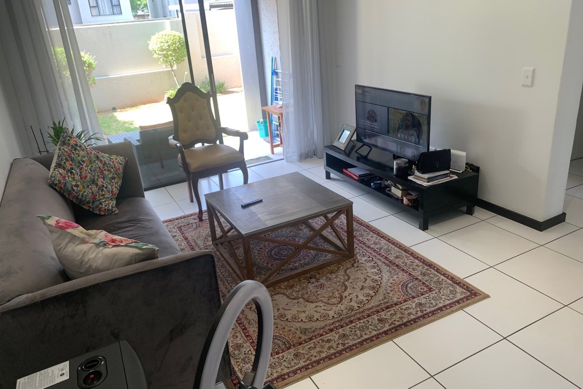 A living room featuring ceramic floor tiles and a large sliding glass door providing access to an outdoor patio area.