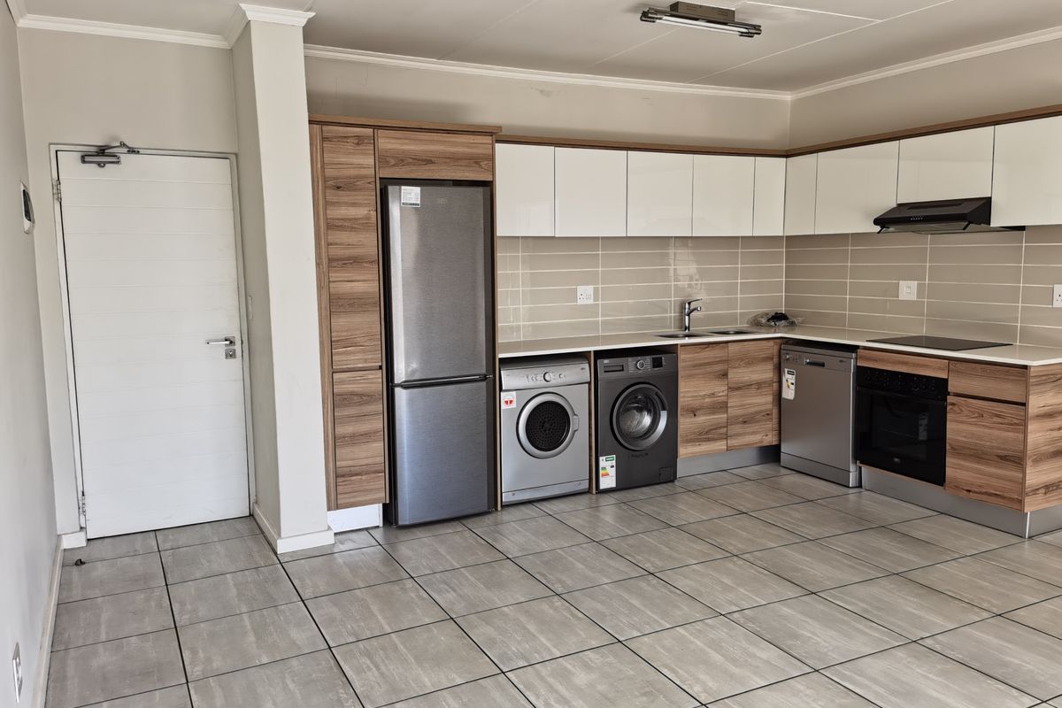Modern kitchen featuring wood-grain and white cabinetry, tiled flooring, integrated oven, extractor fan, and a tiled backsplash in an open-plan layout.