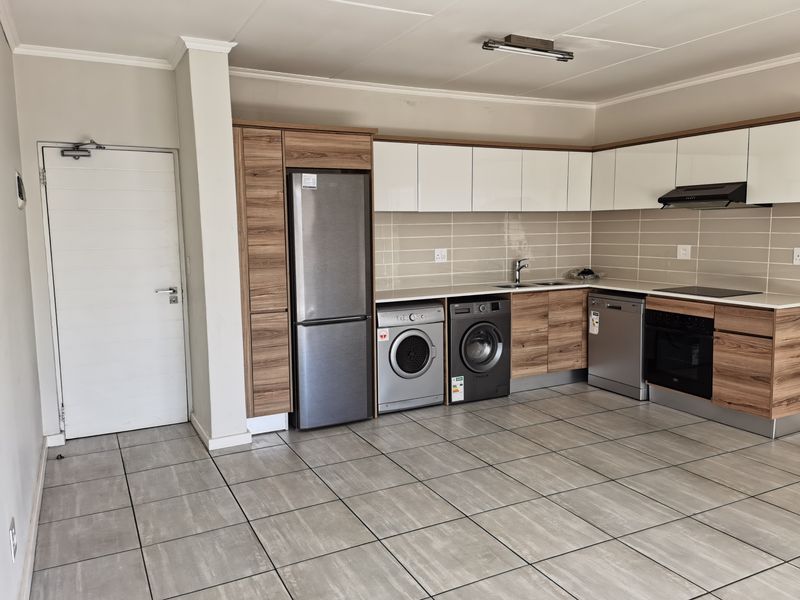 Modern kitchen featuring wood-grain and white cabinetry, tiled flooring, integrated oven, extractor fan, and a tiled backsplash in an open-plan layout.