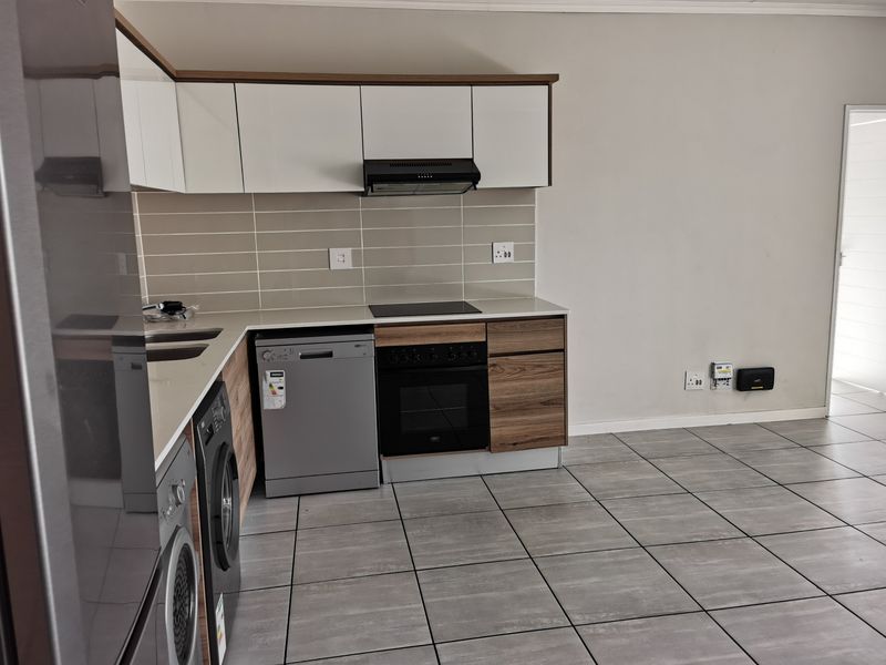 Modern kitchen featuring white and wood-grain cabinetry, tiled backsplash, built-in oven, extractor fan, and tiled flooring in an open-plan layout.