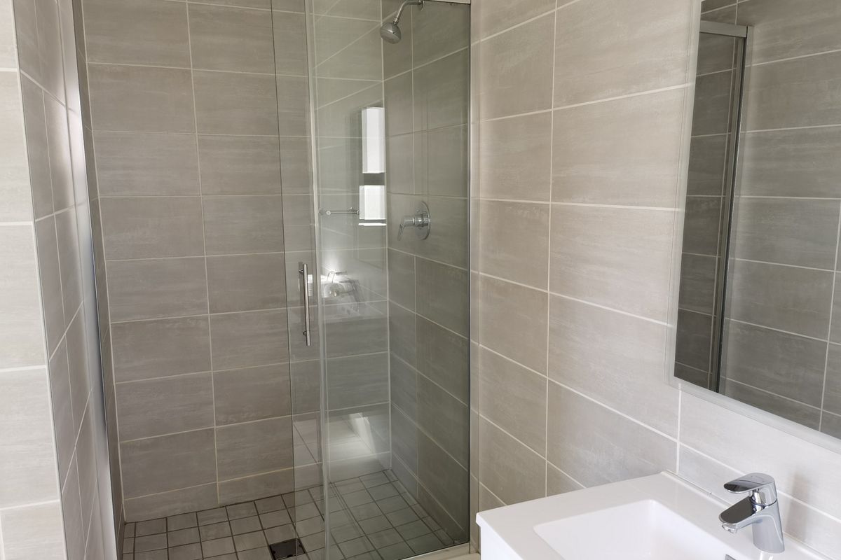 Modern bathroom featuring a glass-enclosed shower, contemporary vanity basin with mixer tap, and neutral wall tiling.