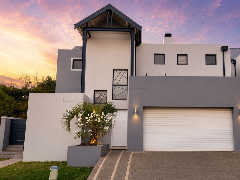 Modern double-story cluster home featuring a clean architectural facade, automated garage, paved driveway, and integrated planter box at the entrance.