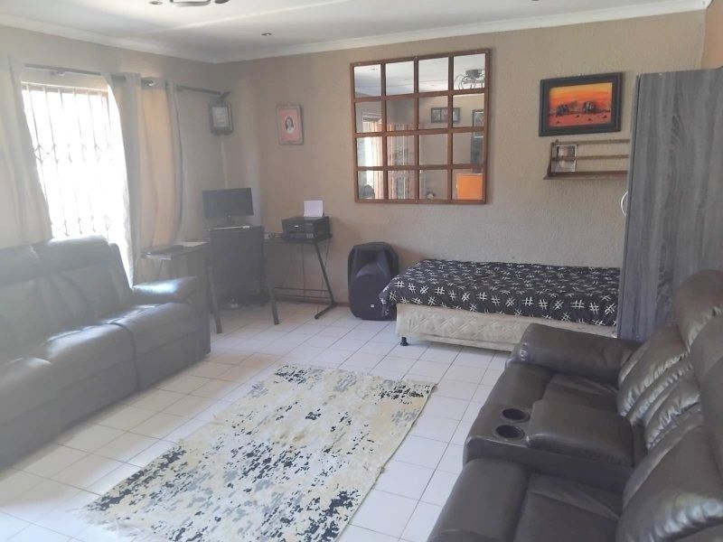 A living room featuring tiled flooring and recessed downlights, providing a functional space with security bars installed on the window.