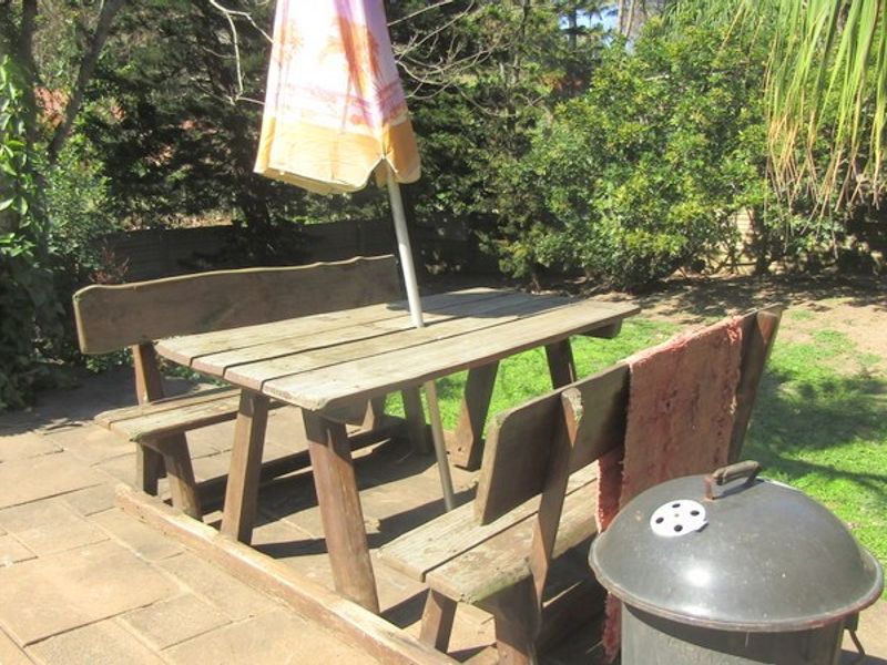 A paved outdoor patio area situated in a garden setting, providing a functional space for outdoor dining and relaxation.