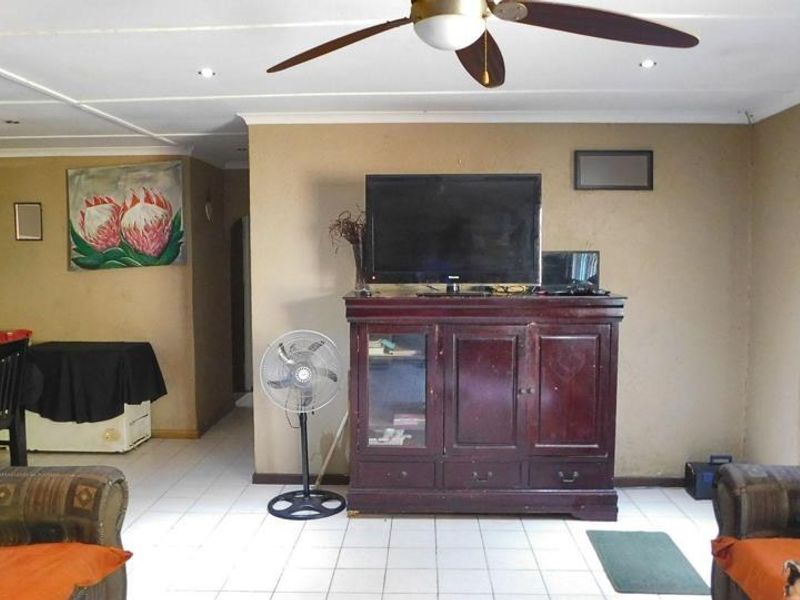 A living room featuring tiled flooring, recessed lighting, and a ceiling fan, with a neutral wall finish and coved cornicing.