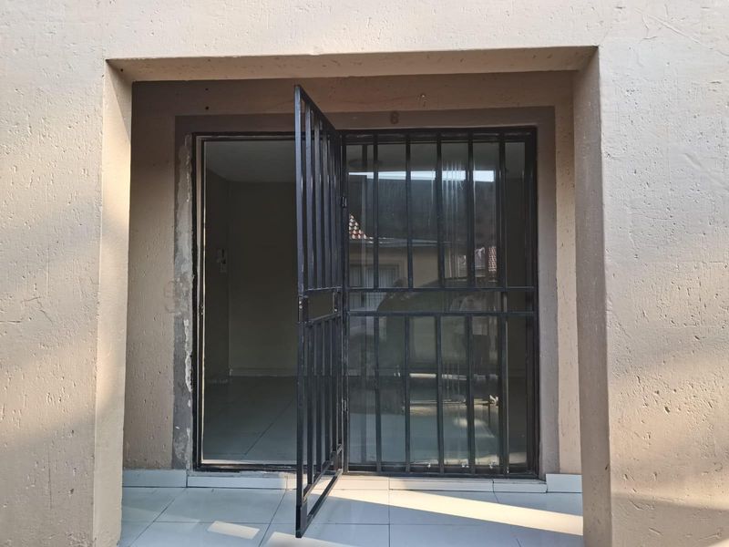 Entrance area featuring a security gate and tiled flooring, showing signs of wear around the door frame requiring maintenance.