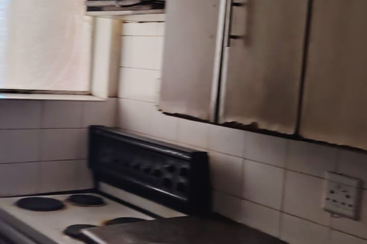 A dated kitchen featuring built-in cabinetry, a freestanding stove, and tiled splashbacks, requiring significant renovation and modernization.
