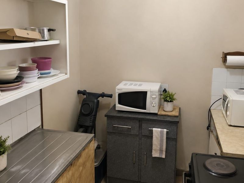 A functional scullery area featuring built-in cabinetry, shelving, and a stainless steel sink, providing additional prep and storage space.