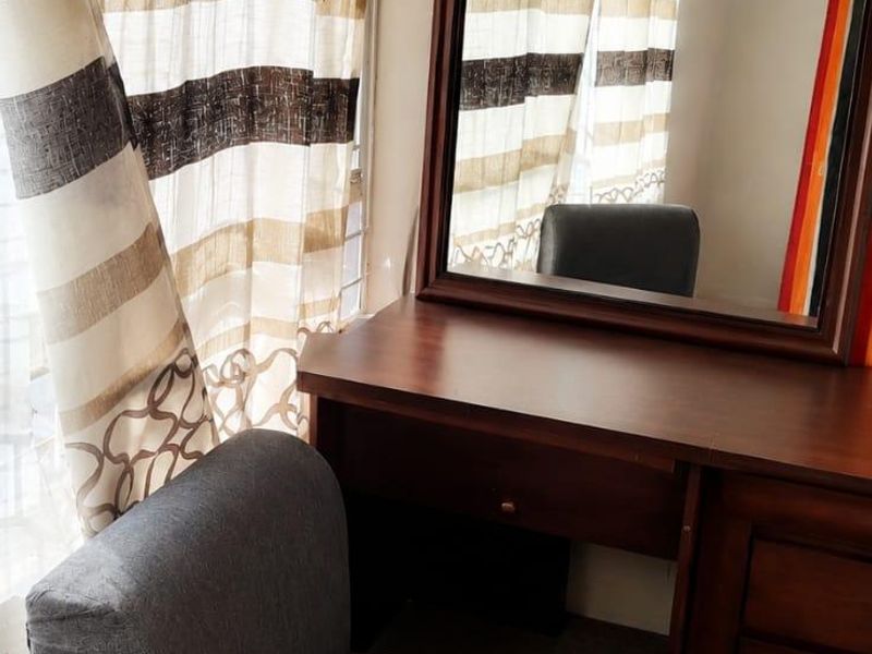 A bedroom corner featuring a window with patterned curtains and carpeted flooring.