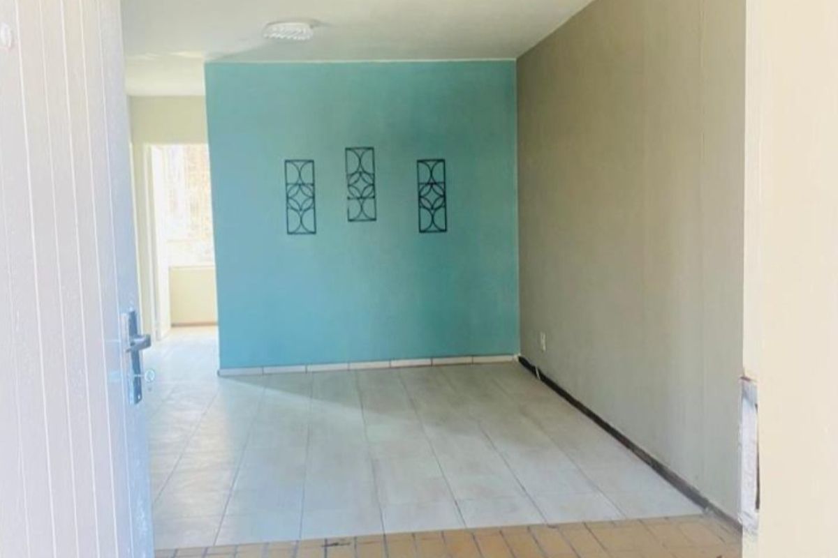 An empty living area featuring tiled flooring and a distinct accent wall, offering a blank canvas for potential interior design updates.