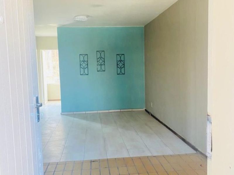 An empty living area featuring tiled flooring and a distinct accent wall, offering a blank canvas for potential interior design updates.