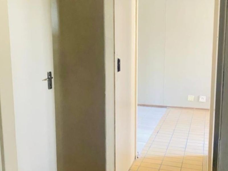 A functional hallway featuring built-in storage cupboards and tiled flooring, leading into an adjacent living space.
