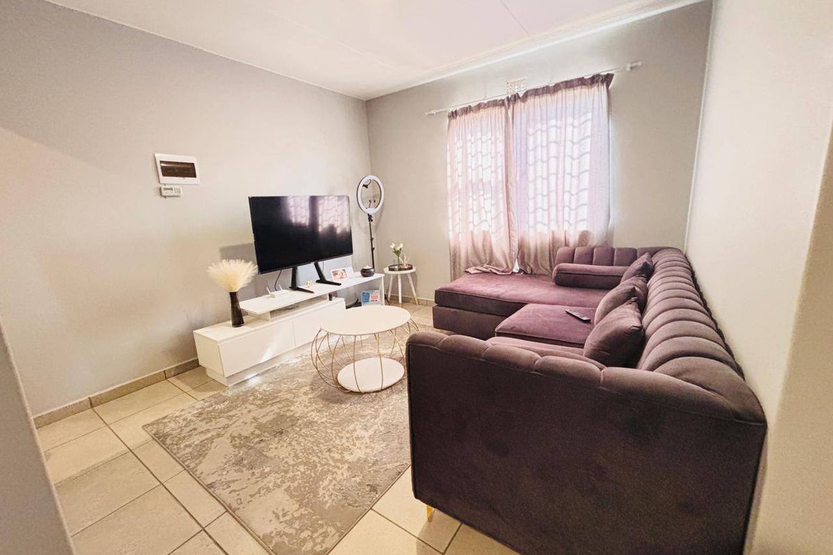 A comfortable living room featuring neutral tiled flooring and natural light through window curtains, providing a functional and inviting space.