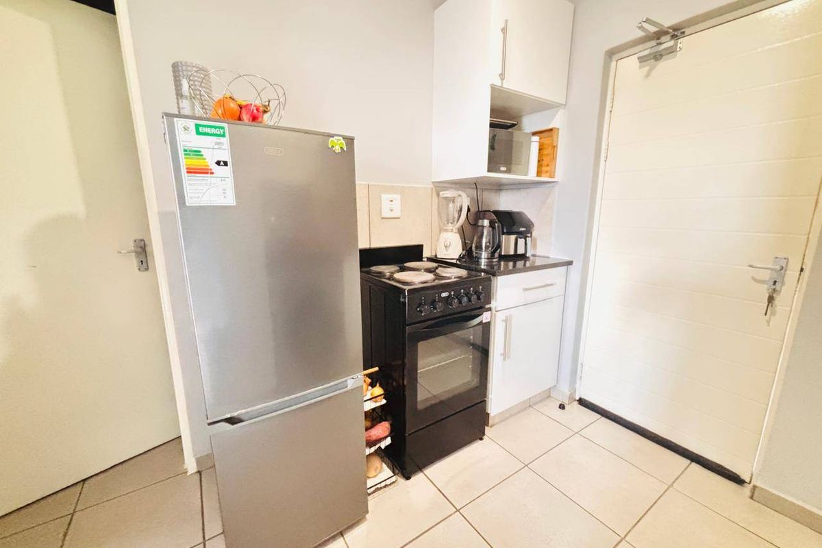 Compact kitchen area featuring tiled flooring, built-in cabinetry, and a freestanding electric stove.