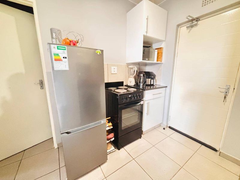 Compact kitchen area featuring tiled flooring, built-in cabinetry, and a freestanding electric stove.