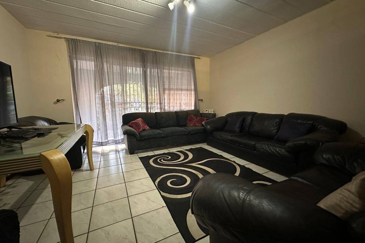 A spacious living room featuring tiled flooring and large sliding glass doors that provide access to the exterior.