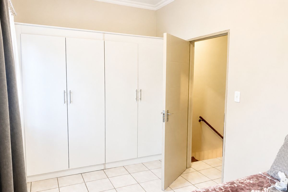 Bedroom featuring white built-in cupboards, tiled flooring, and direct access to an internal staircase.