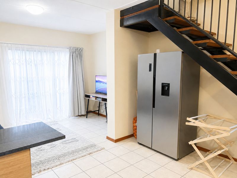 Open plan living area featuring tiled flooring, a modern metal staircase, and a sliding glass door leading to the exterior.