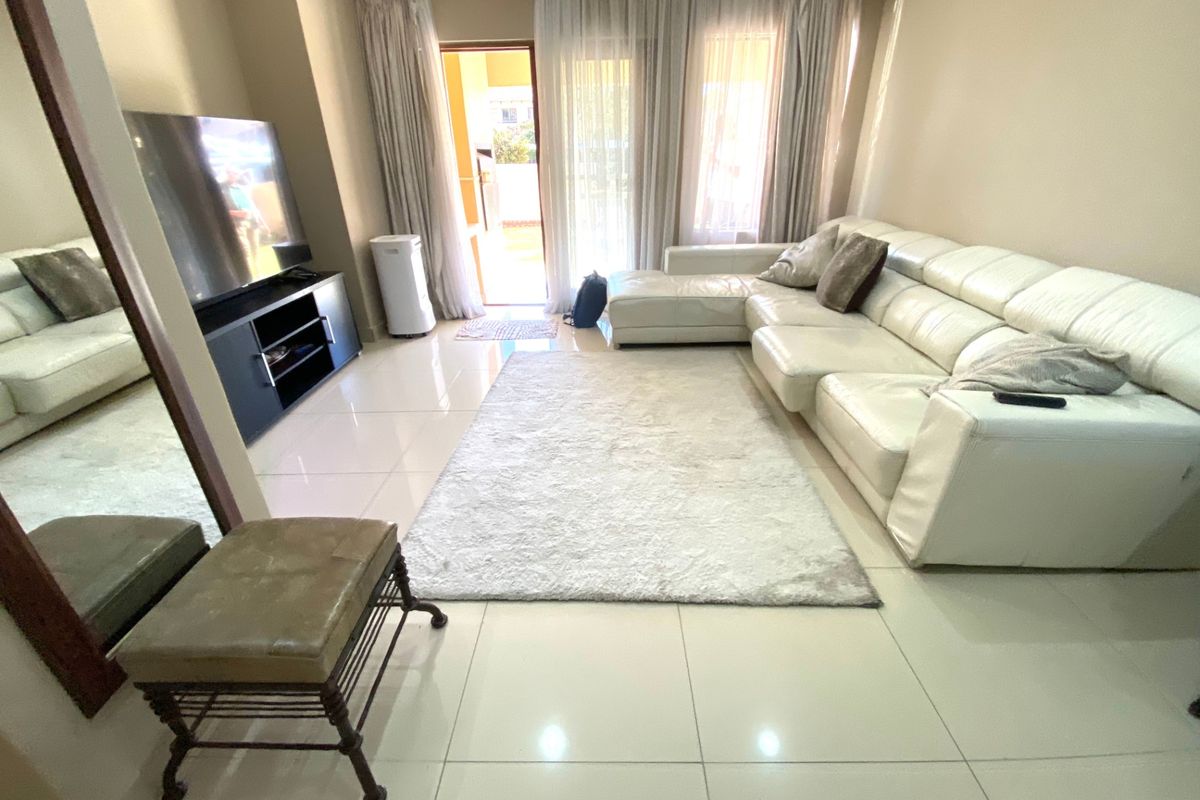 A bright living room featuring large format floor tiles and sliding glass doors that provide access to an outdoor patio area.