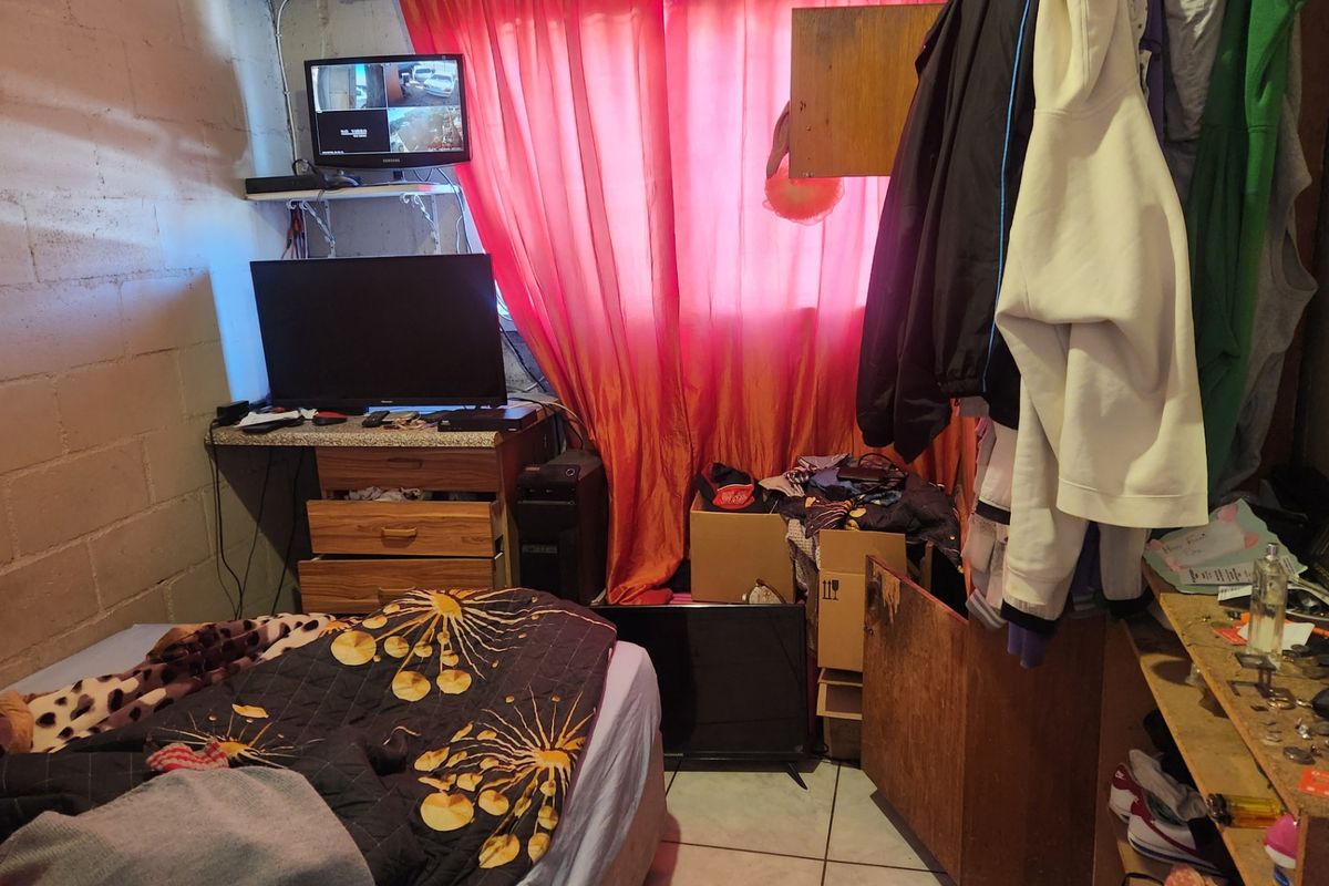 A bedroom featuring exposed concrete block walls and tiled flooring, currently requiring significant cosmetic updates and finishing to improve the overall living space.