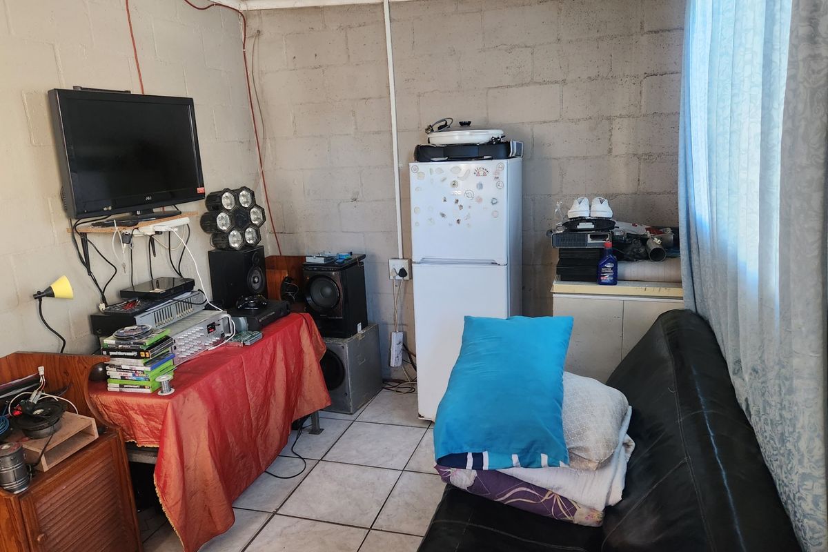 A compact living area featuring tiled floors, exposed concrete block walls, and a tongue and groove ceiling, currently used as a multi-purpose entertainment space.