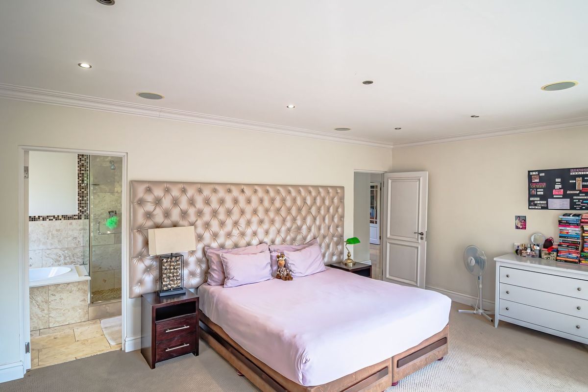 Spacious bedroom featuring neutral walls, crown molding, recessed lighting, and an integrated en-suite bathroom with tiled finishes.