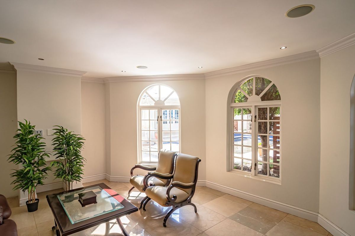 Bright living area featuring elegant arched windows, tiled flooring, recessed ceiling lighting, and integrated ceiling speakers.