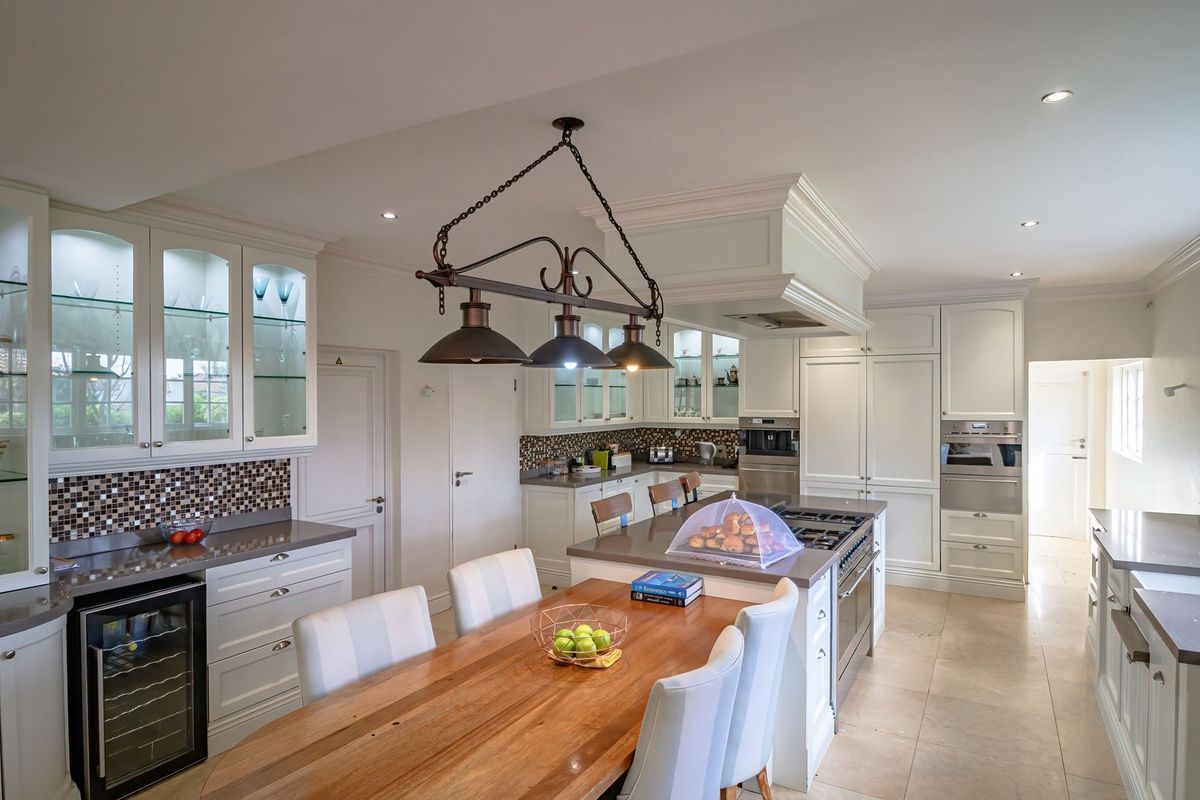 Spacious, well-appointed kitchen featuring custom cabinetry, stone countertops, a central island with integrated cooktop, and high-end built-in appliances.