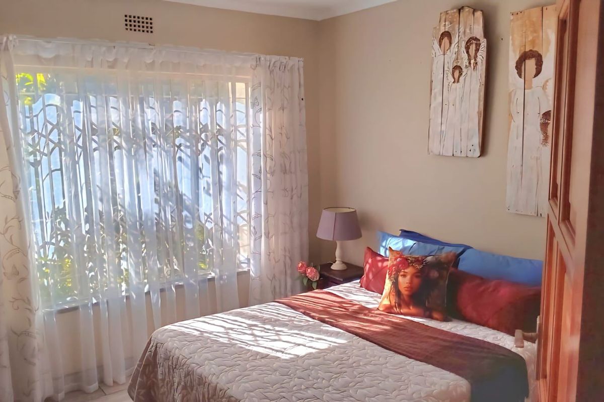 A cozy bedroom featuring a large window that allows for natural light, neutral wall tones, and a functional layout.