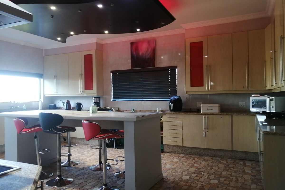 A kitchen featuring built-in cabinetry, granite countertops, a central island, and a distinctive recessed ceiling feature with integrated lighting.