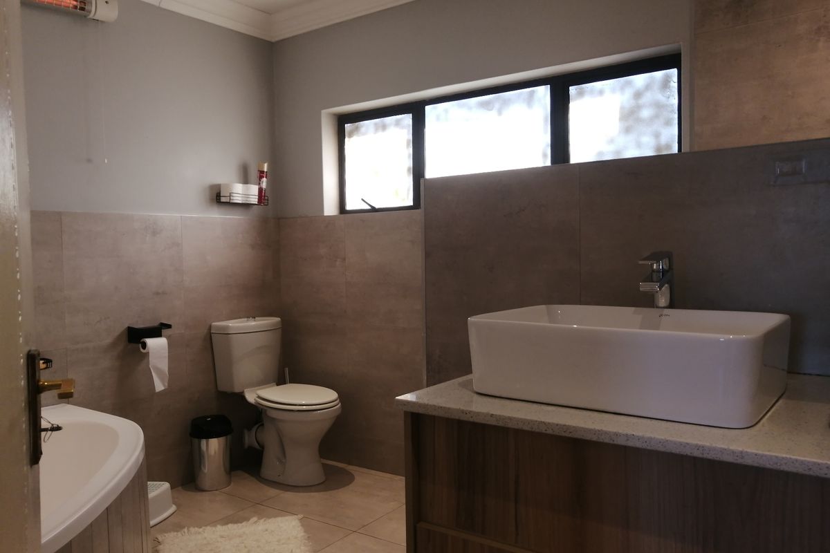 Modern bathroom featuring a vessel sink on a stone-topped vanity, a bathtub, and neutral-toned wall and floor tiling.