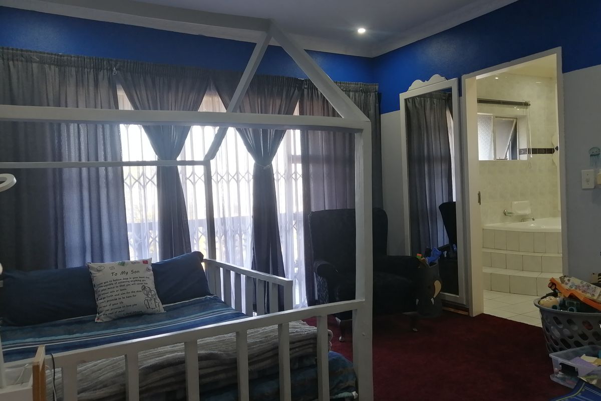 A bedroom featuring an en-suite bathroom with a built-in bathtub, recessed lighting, and security gates over the windows.